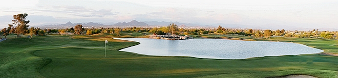 Golf green with water hazard and distant mountains